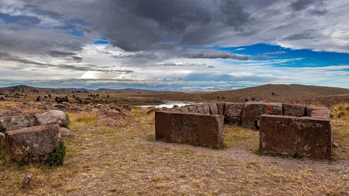 Round stone structures under a dramatic sky in a wide landscape, The Chullpas of Sillustani near