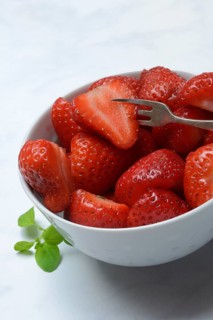 Halved strawberries in a bowl, Fragaria