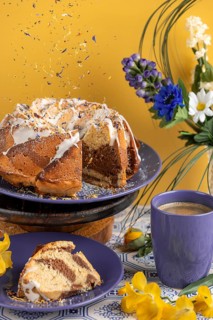 Edible flowers falling on marble cake, cake surrounded by flowers and a cup of coffee, yellow