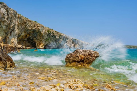 Wellen brechen an einem Felsen im Meer an einem sonnigen Tag auf der Insel Cres, Kroatien
