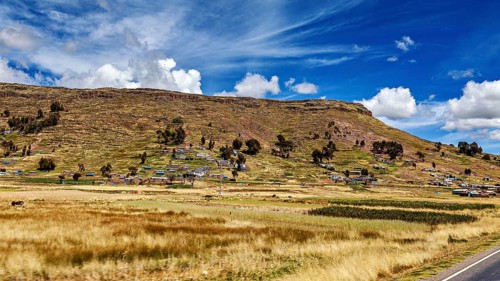 Small village on the foothills of a hill under a blue sky with clouds, The villages and countryside