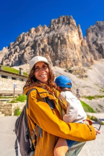 Mother carrying her son while hiking in the beautiful tre cime di lavaredo mountain range,