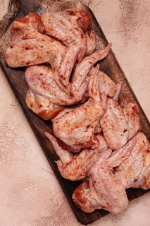 Chicken wings, marinated and laid out on a wooden platter, ready for cooking, grilling or baking,