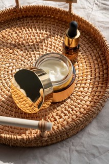 A luxurious skincare set featuring a cosmetic of cream and a dropper bottle on a woven basket. The