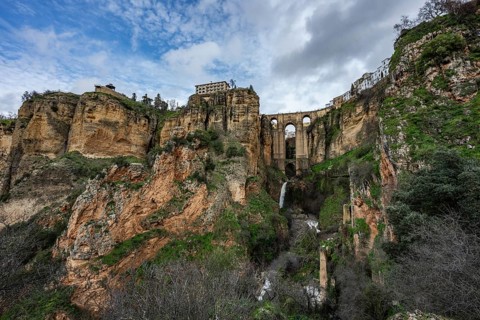 Wide angle view from the bottom of the gorge featuring the massive arches of Puente Nuevo bridge