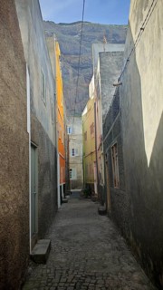 Narrow alley with tall, colorful buildings and a mountain in the background, Ribeira Grande, Santo