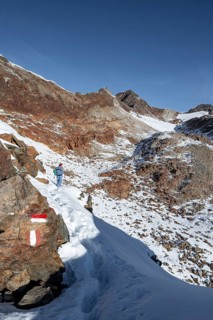 Mountaineer on a hiking trail with snow, ascent to Ramoljoch, autumnal mountain landscape, Ötztal