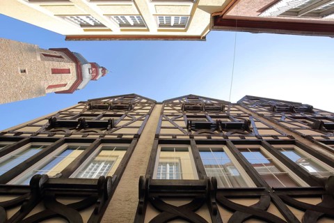 View up to the church tower of St. Martin church built in 1456 and half-timbered houses, looking