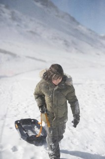 A boy in a green parka pulls a sled through the snow at Sierra Nevada Ski Resort in Granada. The