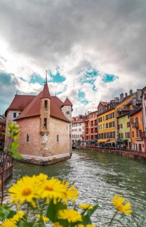 A vibrant view of the Palais de l'Isle and adjacent colorful buildings, set against a dramatic sky