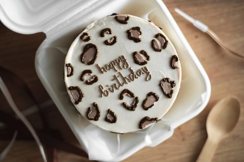 Top view of a beautifully designed Bento birthday cake inside a white takeout box, featuring