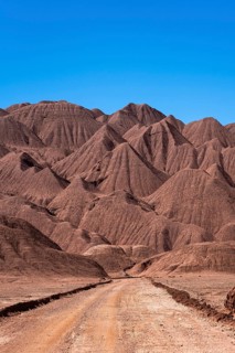 A striking image showcasing a solitary dirt road meandering through the dramatic, eroded mountain