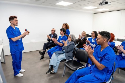 Young medical professional presenting a device during a healthcare seminar, with diverse colleagues