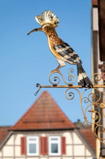 07.04.2026. A traditional golden wrought iron guild sign of a Hoopoe (Upupa epops) above the roofs