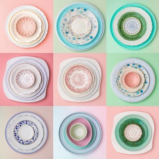 A collage of nine artistic plate arrangements on pastel backgrounds. Each set features different