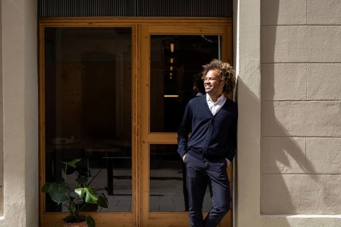 A confident professional enjoys a sunny break outside a trendy coworking space in Barcelona,