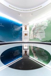 An exhibition space with a large map, bust and reflective surfaces, Bohneberger Showroom Museum