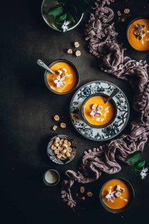 Elegant overhead image showcasing creamy autumn soup garnished with croutons and flowers. Displayed