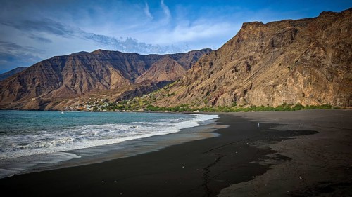 Cliffs form an impressive coastline that meets a dark beach, volcanic sand and wild ocean, hiking,