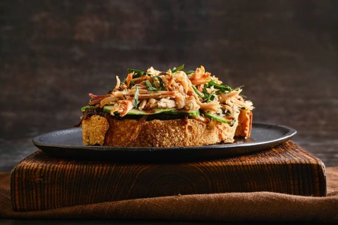 Pulled pork on top of a slice of toast with caramelized onions, cucumber and barbecue sauce. The