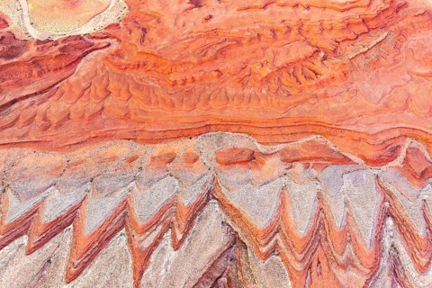 A stunning aerial photograph captures the vivid, natural sandstone patterns and textures near the