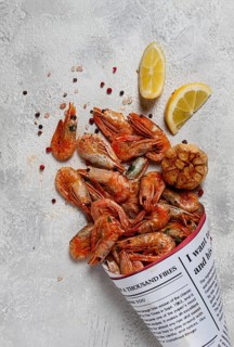 Fried shrimp, in a paper bag, shrimp for beer, in a newspaper, on a gray table, no people