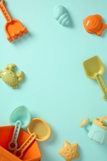 Top view of colorful plastic beach toys frame on blue background with copy space