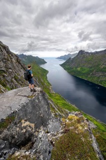 View of Øyfjorden fjord and mountains, view from Barden mountain, young man standing on a cliff,