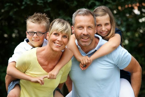 A happy family in the park, four people, man, woman, girl, boy, 8, 9, 35, 45 years piggyback,