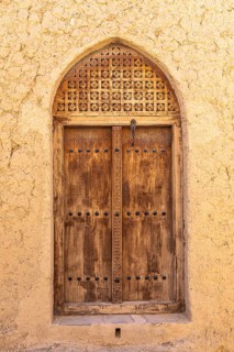 Decorated round arch entrance door in the largest preserved mud town in Oman, Al Bilaad, Al Bilaad