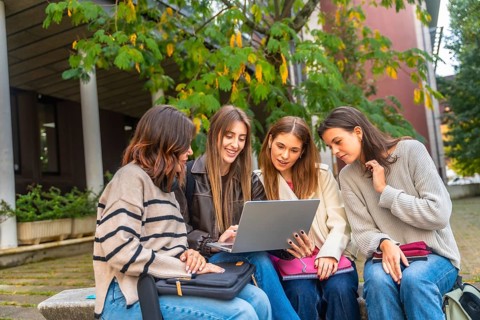 Group of diverse college students studying outdoors on campus, collaborating and working together