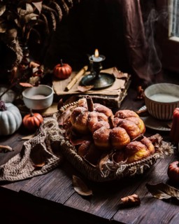 Cozy autumn scene featuring pumpkin-shaped donuts dusted with sugar, surrounded by fall leaves and