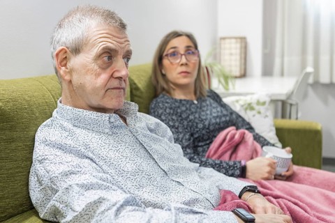 Couple with intellectual disabilities sitting on a green couch at supervised home, wrapped in a