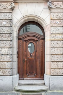 Stylish wooden door, arched door with oval window in a decorative frame in the historic old town of