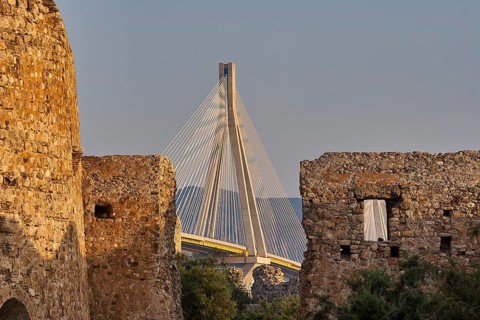 View through castle ruins of a vast modern bridge with mountains in the background, Rio-Antirrio