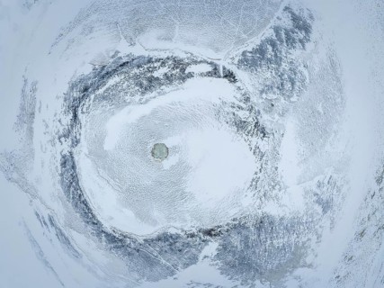Discover the mesmerizing patterns of a snow-covered landscape from above. This aerial shot captures