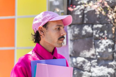 A young Spanish man with a mustache, dressed in vibrant pink, captured while experiencing the city