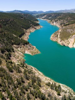 Aerial view of a river meandering through forested mountains with calm blue water, aerial view,