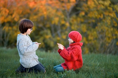 Siblings, enjoy a playful day outdoors in a park surrounded by autumn colors. The boy wears a cozy