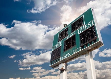HIgh School Score Board on a Dramatic Blue Sky with Clouds and Sun Rays