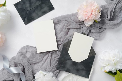 Elegant wedding stationery set with dark envelopes and blank cards. Accompanied by soft gray fabric