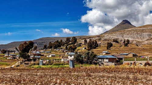 Small village in a hilly landscape with a mountain backdrop and a blue sky, The villages and