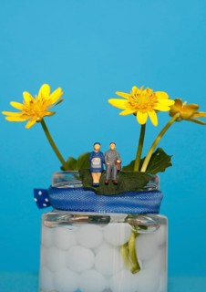 Miniature figures of a man and woman sitting on a vase with yellow flowers, North Rhine-Westphalia,