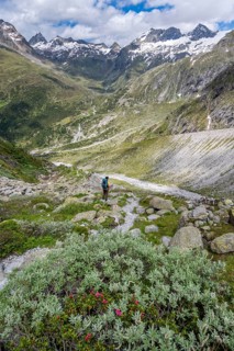 Mountaineer on a hiking trail in front of a picturesque mountain landscape, rocky mountain peaks