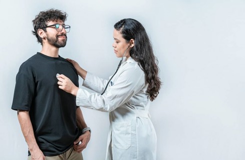 Asian doctor checking a patient heartbeat with a stethoscope. Young Asian doctor checking a male