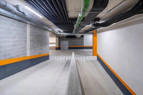This image showcases a well-lit, modern underground parking garage with vibrant orange and white