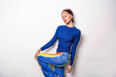 Fashion-forward woman in a striking blue top and multicolored trousers, radiating confidence