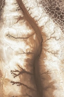 Aerial view showcasing an intricate pattern of winding cracks and textures in a desert landscape,