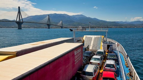 View from a ferry with cars, bridge and mountains under clear sky, Rio-Antirrio ferry, cable-stayed