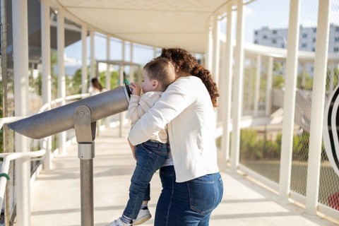 A touching moment captured of a mother holding her baby as they explore a park together. The baby